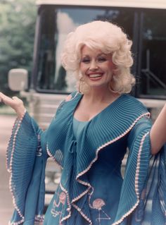 a woman in a blue dress standing next to a bus