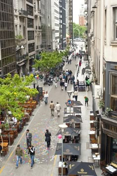 an overhead view of people walking down the street with many tables and umbrellas on it