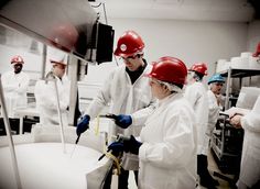 several people wearing hard hats and working in a factory