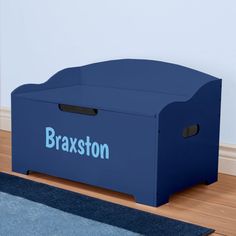 a blue toy box sitting on top of a wooden floor next to a rug and wall