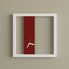 a red and white clock mounted to the side of a wall in a square frame