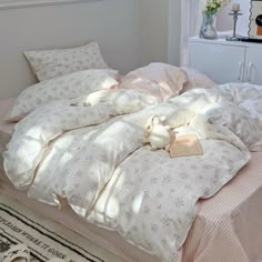 an unmade bed with white sheets and pink comforter in a bedroom area next to a window