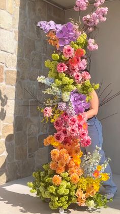 a woman standing next to a tall vase filled with flowers