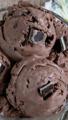 three scoops of chocolate ice cream in a glass bowl