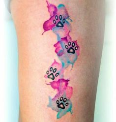 the back of a woman's thigh with watercolor tattoos on her leg and paw prints