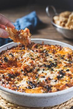 someone is taking a piece of pizza from the casserole dish