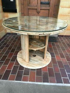 a round glass table sitting on top of a red brick floor next to a wooden door