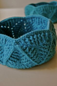 two crocheted blue baskets sitting on top of a white table next to each other