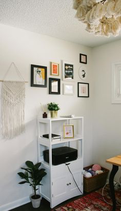 a room with pictures on the wall and a table in front of it, along with a rug