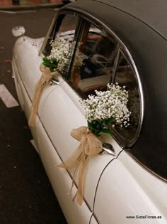 wedding car decorated with baby's breath flowers and burlap ribbon tied to the side