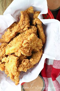 fried chicken tenders in a basket with dipping sauce on the side and red checkered table cloth