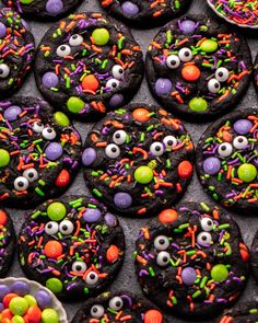 cookies decorated with sprinkles and candy eyes are displayed on a table for halloween