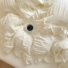 an empty cup is placed in the middle of a white comforter with ruffled edges