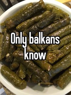 there is a white bowl full of stuffed grape leaves with the words only balkans know