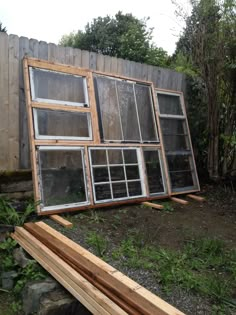 an old window sitting on the side of a wooden building next to a pile of wood