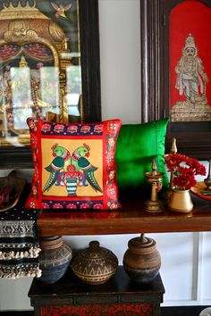 an assortment of decorative items displayed on a shelf in front of a mirror and framed artwork