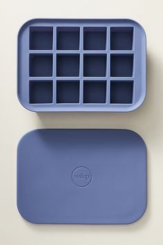 two blue trays with ice cubes in them on a white surface, next to each other