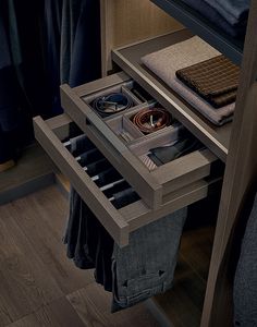 an open drawer on the side of a bed with clothes and other items in it