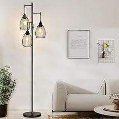 a living room with a white couch and three lights on the floor next to a potted plant