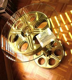 a glass table topped with a gold film reel on top of a hard wood floor