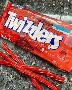 a bag of twists candy sitting on top of a granite counter next to a pile of strawberries