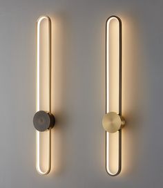 two wall lights that are next to each other on a white wall and one has a round light in the middle