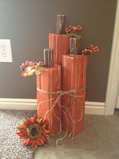 a stack of wooden sticks with flowers tied to them in front of a gray wall