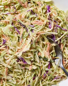 a white bowl filled with coleslaw slaw and a serving spoon in it