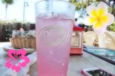 a pink drink sitting on top of a table next to a cell phone and flower