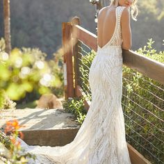 a woman in a wedding dress standing on a bridge