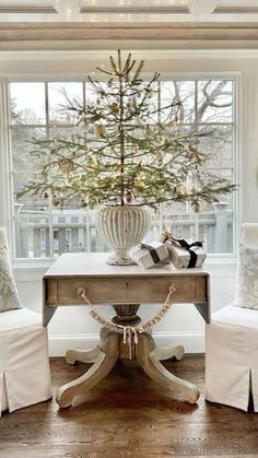 a christmas tree sits in the center of a room with two chairs and a table