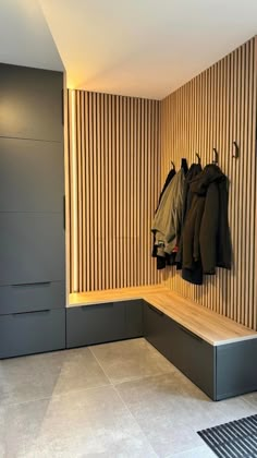 a coat rack with coats hanging on it in front of a wooden paneled wall