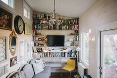 a living room filled with furniture and a flat screen tv on top of a book shelf