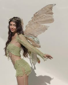 a beautiful woman in a green costume with wings on her head and hands behind her back