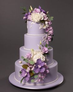 a three tiered cake with purple and white flowers