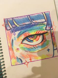 a drawing of an eye with colored pencils on paper next to a notepad