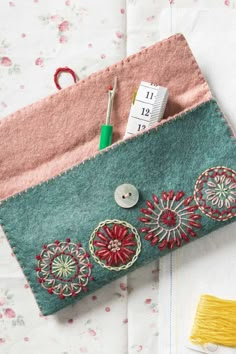 a close up of a bag on a table with scissors and sewing needles in it