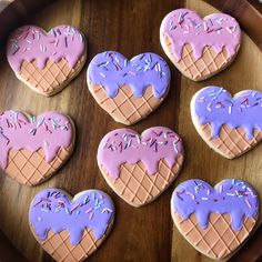 six decorated heart shaped cookies sitting on top of a wooden table