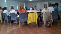 a group of people sitting around a table with laptops and chairs in front of them