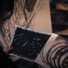 someone is holding up some drawings in their hands and looking at them with evil eyes