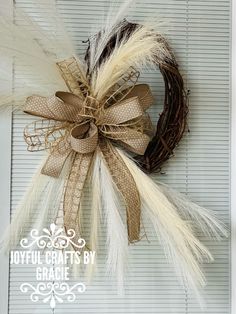 a wreath with feathers hanging on the side of a door that says joyful crafts by craneie