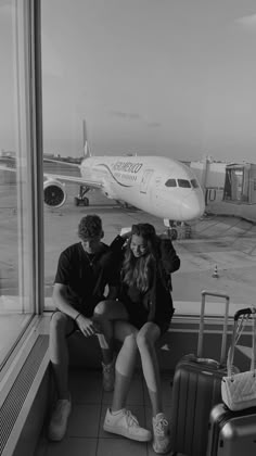 black and white photograph of two people sitting in front of an airport window