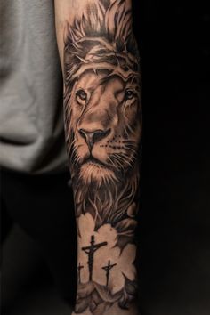 a man's arm with a lion and cross tattoo on the left side of his arm