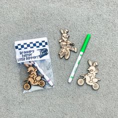 three wooden keychains and two markers on the ground