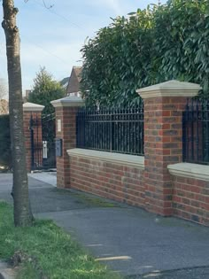 a brick wall with two benches on the side and trees in the back ground behind it