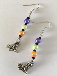 a pair of earrings with colorful beads and silver charms on white background, close up