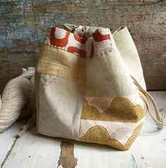 a small bag sitting on top of a wooden floor next to a ball of yarn