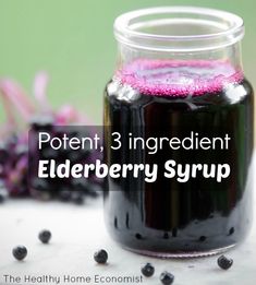 a jar filled with elderberry syrup next to berries