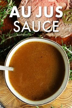 a bowl of soup on a plate with meat and herbs in the background text reads au jus sauce