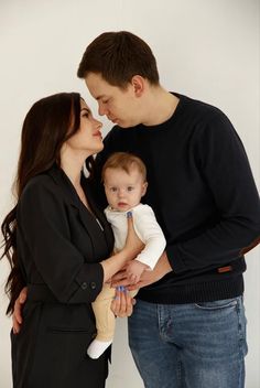 a man and woman holding a baby in their arms while standing next to each other